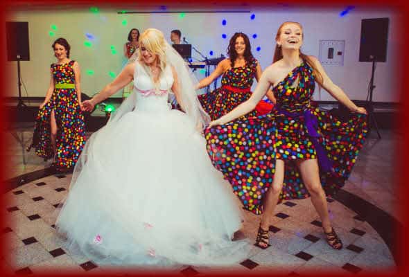 Laughing Bride and Bridesmaids having an awesomely fun time dancing together in a "Special Wedding Party Dance Performance" at her wedding